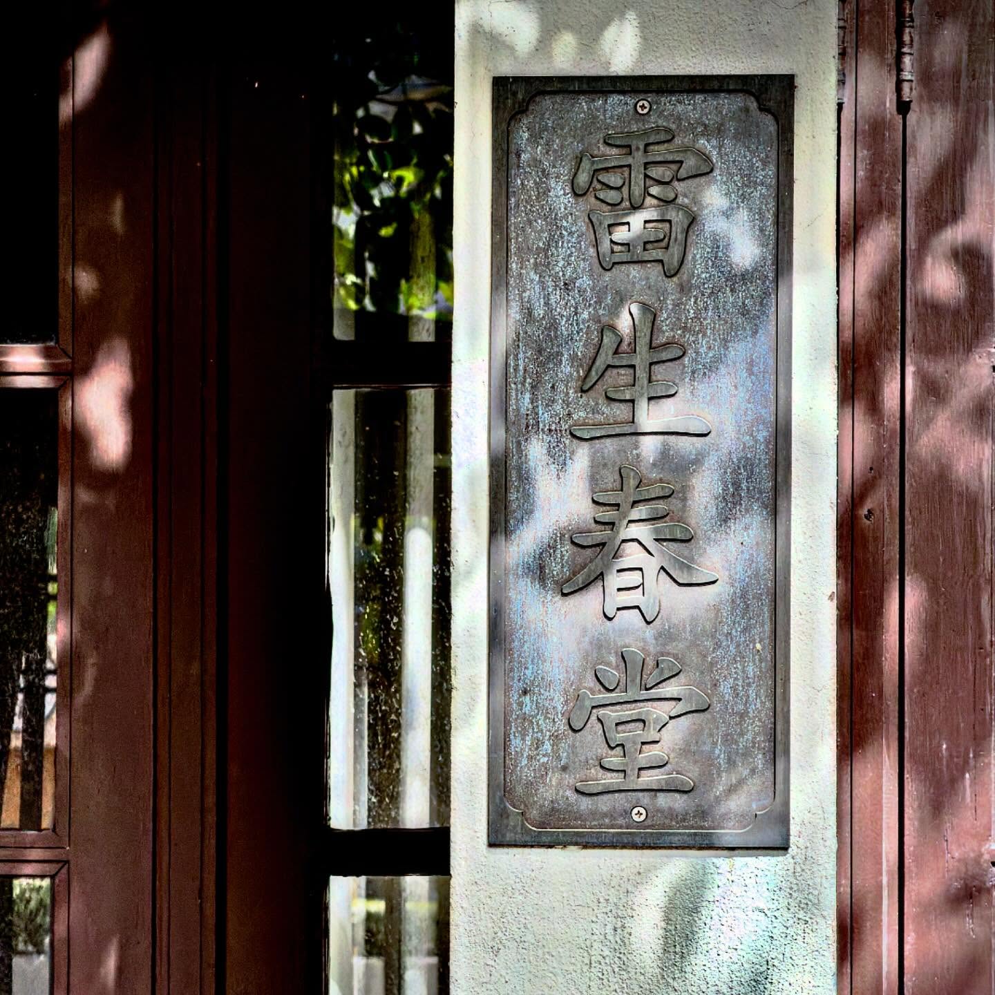 Old Hong Kong doorway with a weathered Chinese sign and dappled shadow