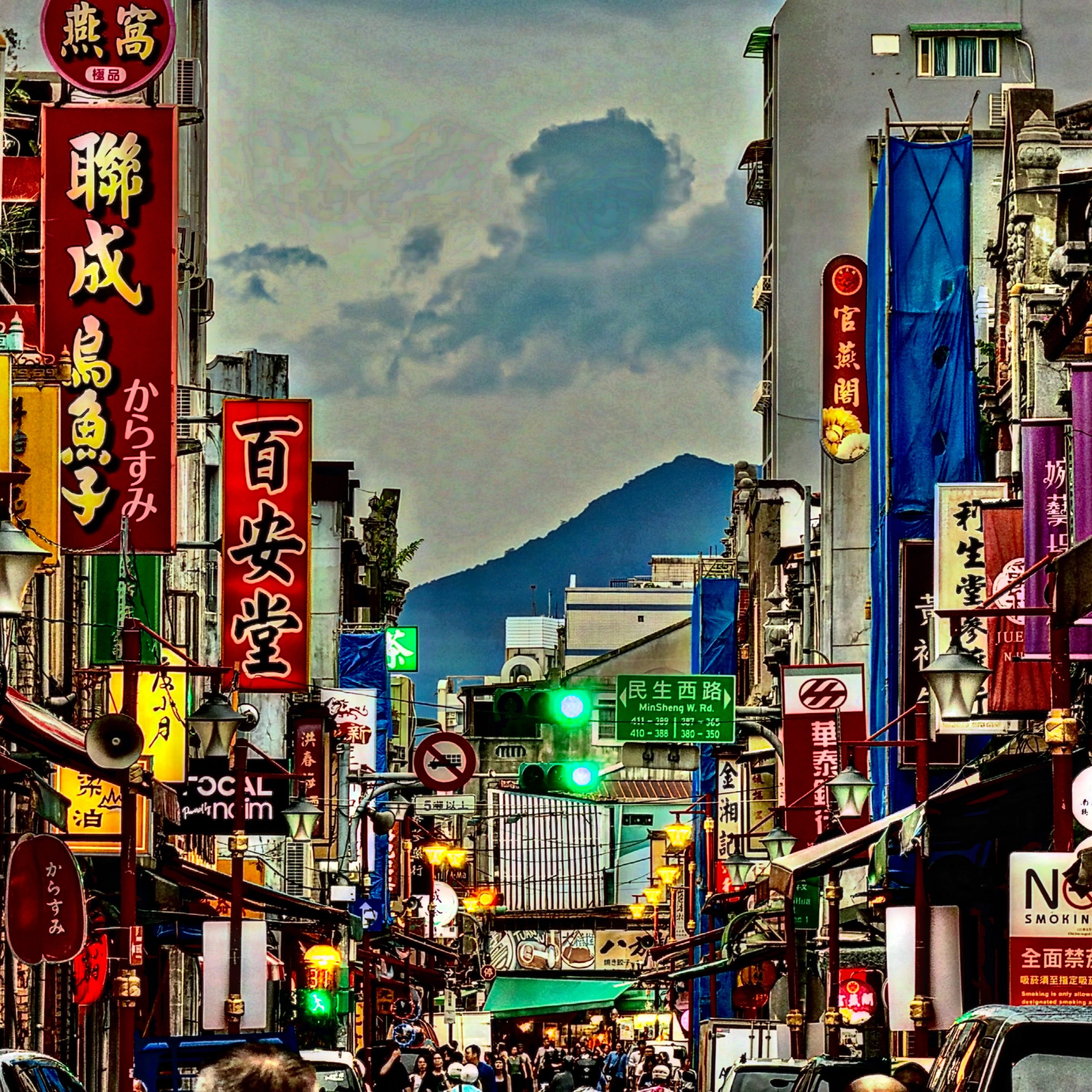 Rows of colourful lanterns filling a Hong Kong street beneath a hazy mountain sky